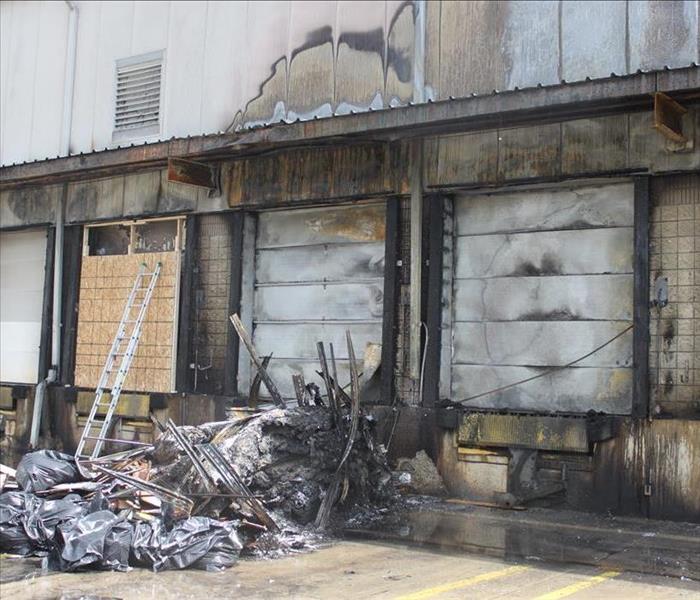 Fire damage to commercial facility with board covering doorway.